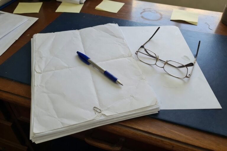 Processo impresso, caneta e oculos sobre mesa de advocacia: danos morais e indenizacao